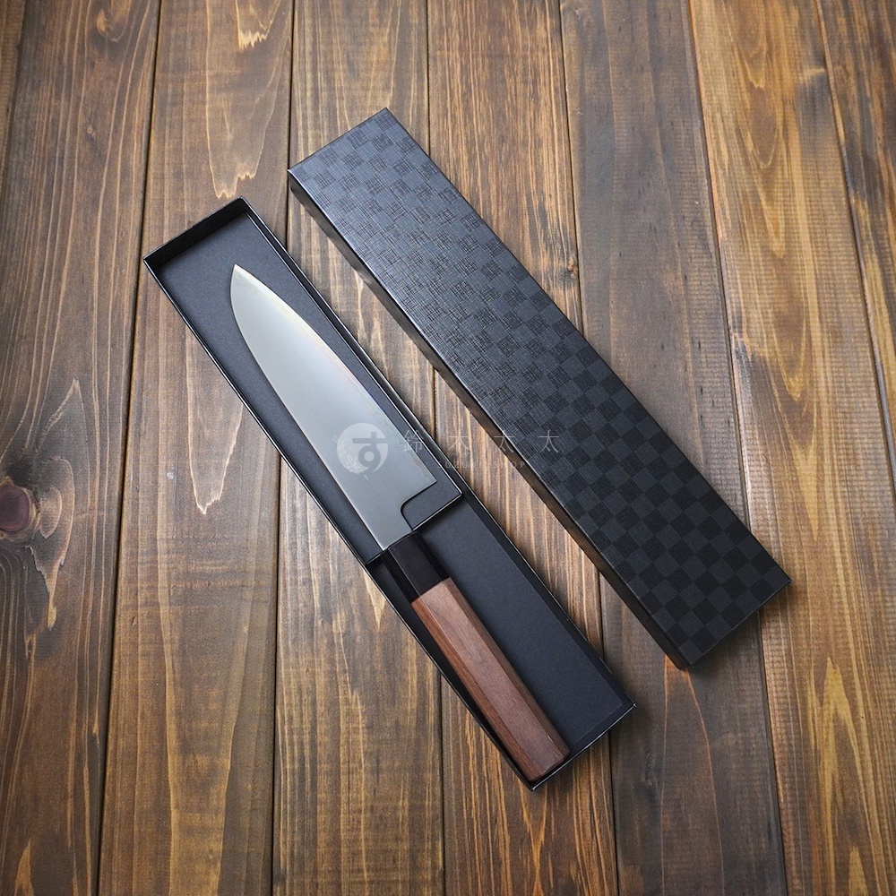 景清 Chromax 鋼三德刀，刀身銀色，握把為胡桃木材質，呈八角形，收納於黑色格紋禮盒中。
