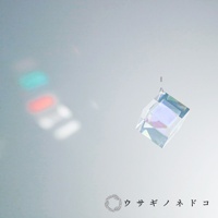 透明玻璃稜鏡立方塊吊飾，懸掛於細線上，折射出七彩光芒，左側牆壁上投射出紅、綠、白色的光斑。