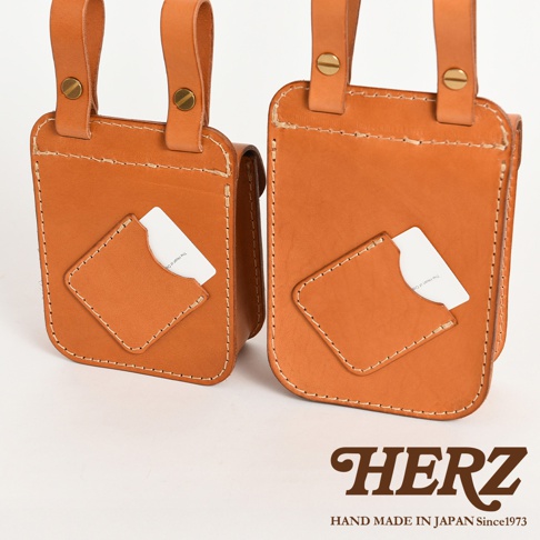 兩個棕褐色皮革腰袋，正面各有菱形嵌皮和小卡槽，頂部有皮革掛帶和金屬釦，手工縫線明顯。