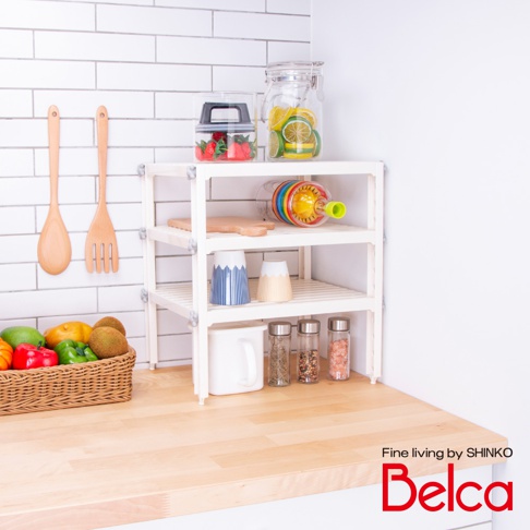 白色三層迷你收納架，架上擺放著玻璃罐裝草莓、檸檬片、七彩榨汁器、木質砧板、藍白條紋杯、米色杯、白色馬克杯及多罐調味料，架旁有木質湯勺與叉子，前方籃子裡有水果與蔬菜。