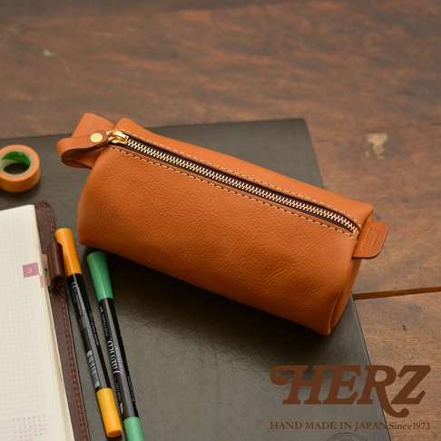 職人手作皮革多用途收納筆袋，採用天然皮革製成，呈現溫潤的棕褐色。筆袋設計簡潔，拉鍊開合，兩側有皮革提把，可收納筆、文具等小物。