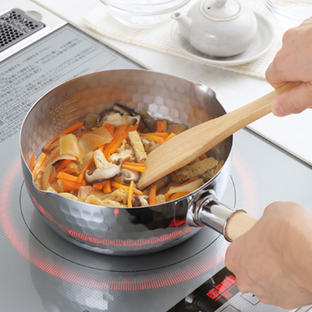 不鏽鋼單柄雪平鍋，鍋內裝有胡蘿蔔、香菇、豆皮等食材，正在烹煮，鍋身有刻度標示。