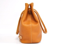 淺棕色皮革束口包，有兩條皮革提把，包身有白色縫線，側面下方有皮革飾釦。