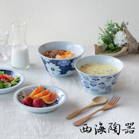 波佐見燒藍花紋兩件式丼飯碗，淺藍色碗身繪有深藍色花朵圖案，碗內裝有麥片優格、水果丁、玉米濃湯及沙拉，另有木製湯匙和叉子，整體風格清新。