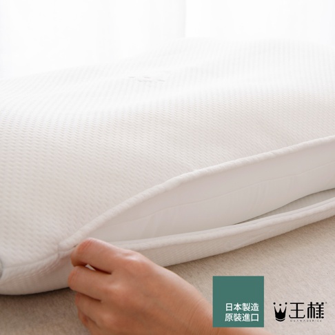白色王樣の極柔枕，枕套為天絲材質，表面有細緻的織紋，一隻手正在拉開枕套的拉鍊。
