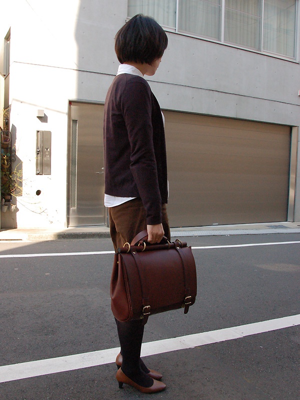 職人手作皮革屋瓦風三用側背包，深棕色皮革材質，帶有金色金屬扣環和提把，可手提、側背或斜背。