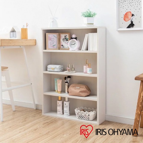 白色四層收納書櫃，擺放有相框、鬧鐘、書籍、化妝品、保養品與裝飾籃等物品。