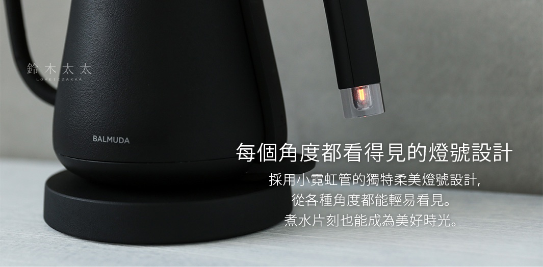 黑色 BALMUDA 絕美手沖壺，壺身呈現霧面質感，搭配細長的壺嘴，壺嘴末端有透明材質包裹的橙色指示燈。