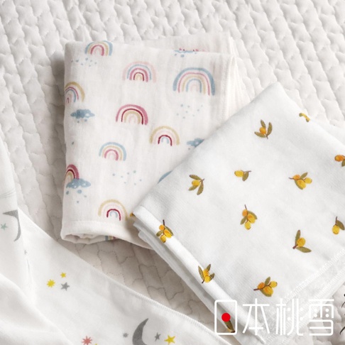 兩條白色紗布方巾，一條印有彩虹和雲朵圖案，另一條印有黃色小果實圖案，下方為印有月亮和星星的白色布條。