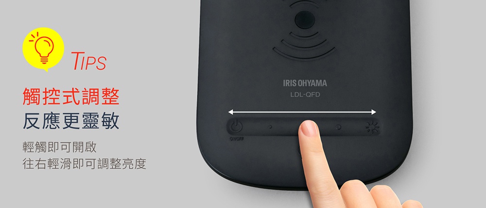 黑色霧面質感的 IRIS OHYAMA LDL-QFD 無線充電盤檯燈，頂部有無線充電標誌，下方設有觸控按鈕，手指正在觸碰調整亮度的按鈕。