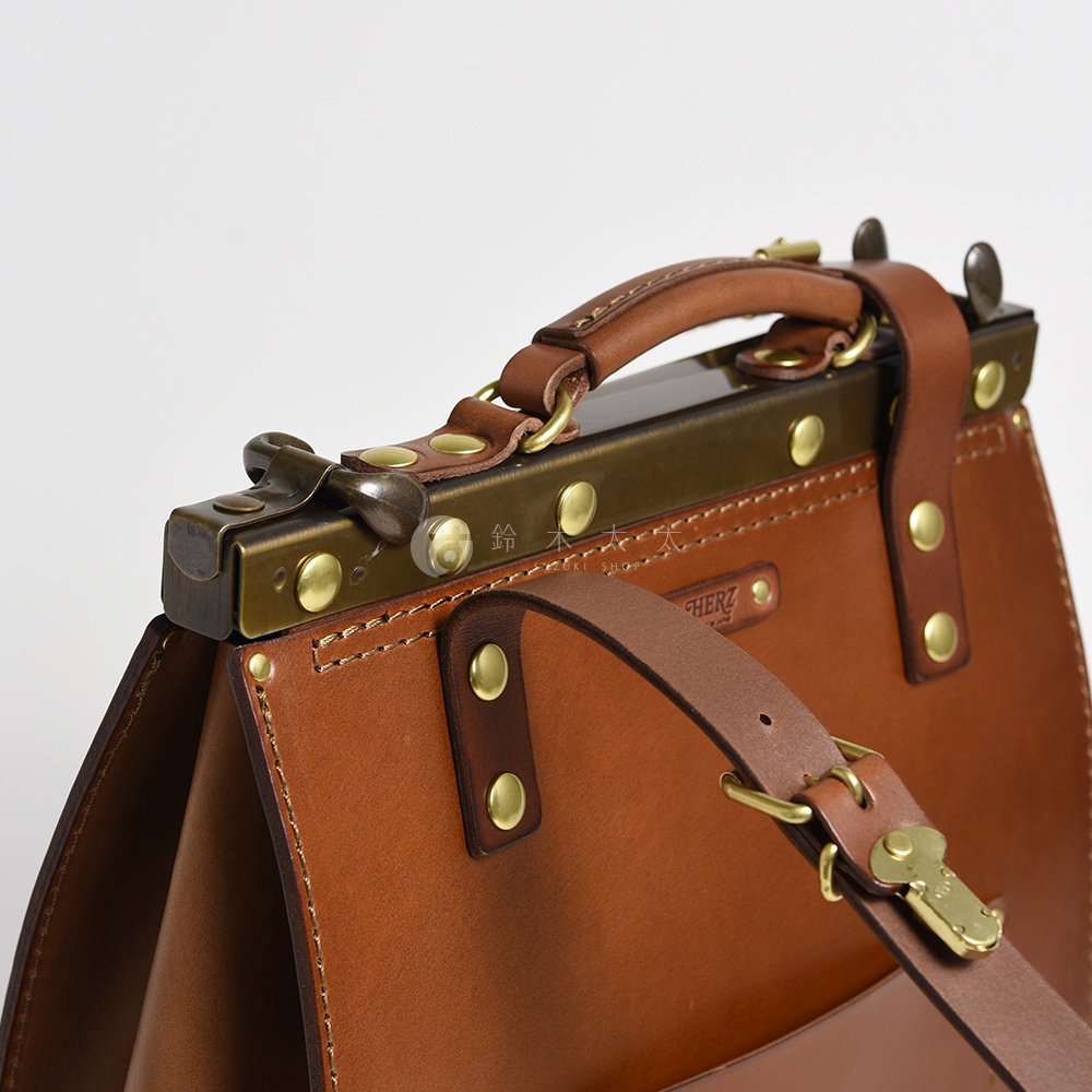 棕色皮革復古口金後背包，特寫頂部提把、金屬鎖扣和車縫細節。