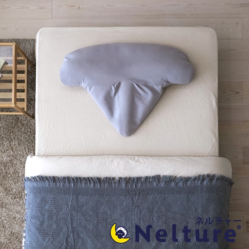 灰色瑜珈感安睡枕，呈扇形，中央有凹陷設計，放置於米白色床單上，枕頭下方覆蓋有灰色織紋毯子。