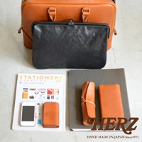 職人手作皮革Organ商務公事包，搭配黑色皮革長夾，旁邊有橘色皮革筆袋、卡夾、手機及雜誌。
