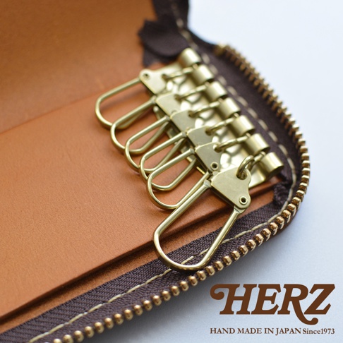 職人手作皮革鑰匙包，內有六個黃銅掛鉤，拉鍊部分為深棕色，搭配焦糖色皮革內襯。