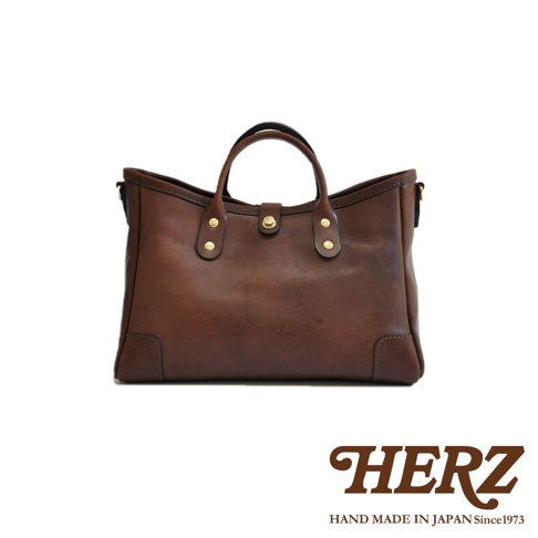 職人手作皮革托特包，深棕色，簡約設計，配有雙提把和金色金屬扣，適合日常攜帶。