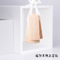 數塊淺棕色、紋理明顯的天然樟木條，以白色繩索串起懸掛，背景為白色方框。