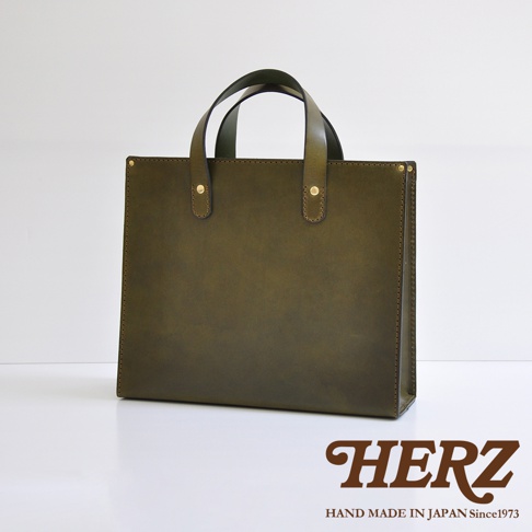職人手作皮革直式托特包，橄欖綠色，光滑皮革材質，配有兩條皮革提把，由黃銅鉚釘固定。