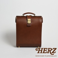 棕色皮革手作杜勒斯商務後背包，配有金色金屬鎖扣、手提把和四個底部支撐腳。