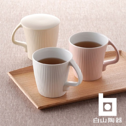 三個陶瓷馬克杯，分別為米白色（附蓋）、白色和粉紅色，杯身皆有直條紋，放置於木質托盤上。