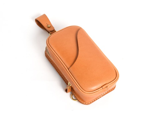 職人手作皮革兩用直立型斜背包，採用淺棕色皮革，帶有縫線細節，正面有弧形設計，附有拉鍊開合及掛環。