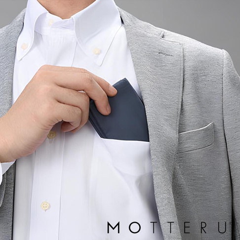 手持一個深藍色的摺疊環保隨行袋，放入白襯衫的胸前口袋。隨行袋材質光滑，邊緣清晰，展示其小巧便攜的特性。