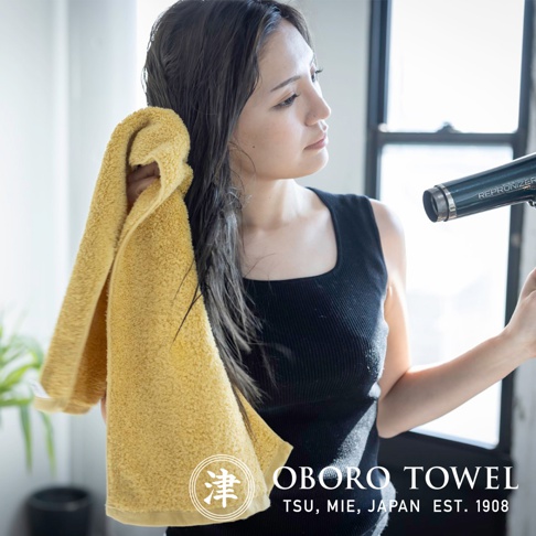 黃色毛巾擦拭濕髮的特寫，毛巾材質柔軟蓬鬆，展現良好的吸水性。