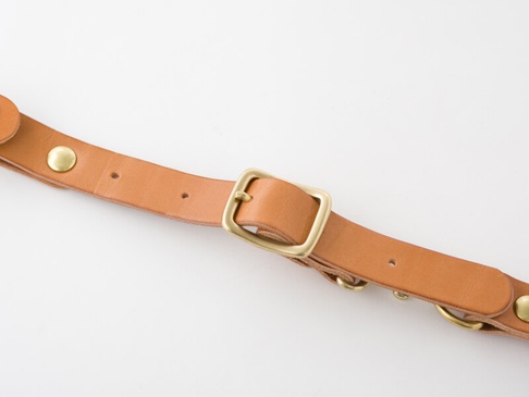 職人手作皮革背包用減壓胸前扣帶 (KO-2) 的特寫，展示淺棕色皮革帶，配有黃銅色帶扣、鉚釘和 D 形環。