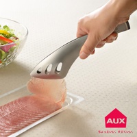 一只手使用不鏽鋼料理夾，夾取一層薄切生魚片，生魚片放在透明塑膠包裝盒中。左側有一個玻璃碗，裝有色彩鮮豔的沙拉。