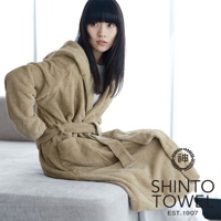 身穿米色蓬厚長袖連帽浴袍的女子，浴袍以腰帶繫住，材質柔軟，整體呈現舒適感。