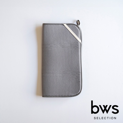 灰色可折疊收納瀝水墊，表面有細小的網狀紋理，邊緣為深灰色，一側配有米白色綁帶和掛環。