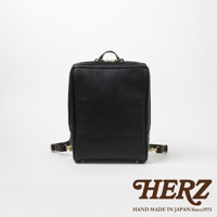 黑色皮革方形商務後背包，設有金色拉鍊和可調節肩帶，側面有編織紋理。