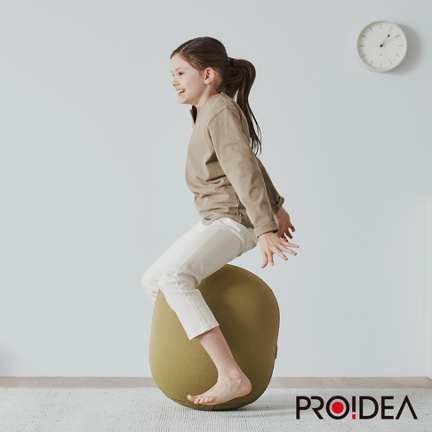 一名年輕女孩坐在橄欖綠的 MALLOW Knit 收納彈力平衡球上，該平衡球為迷你款，材質為針織，表面有紋理。