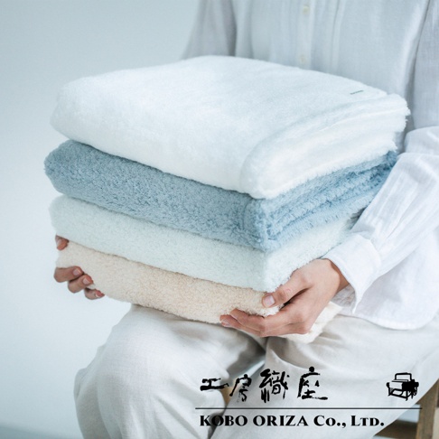 堆疊四條今治柔感極甘撚系匹馬棉浴巾，顏色由上至下分別為白色、淺藍色、淺綠色及米黃色，質地蓬鬆柔軟。