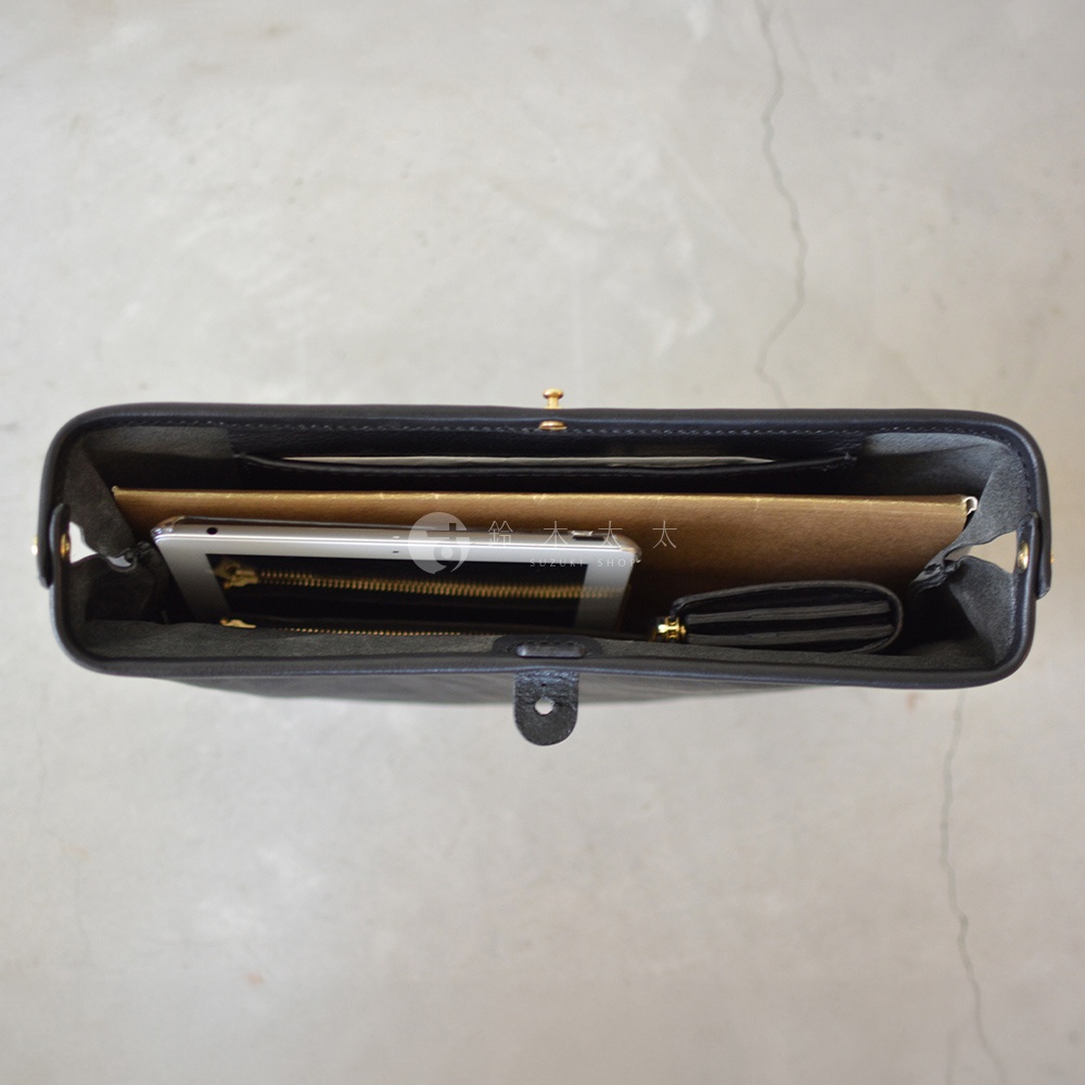 黑色皮革手拿包，內部裝有平板電腦、筆記本和條紋零錢包。