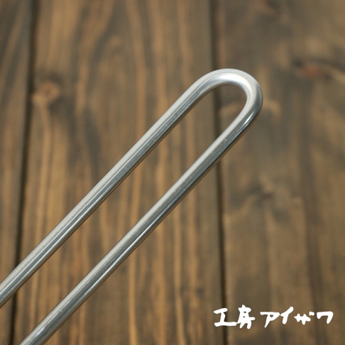 不鏽鋼雙口牛奶鍋的鍋柄，呈現金屬銀色，採用圓弧形設計，材質為不鏽鋼。