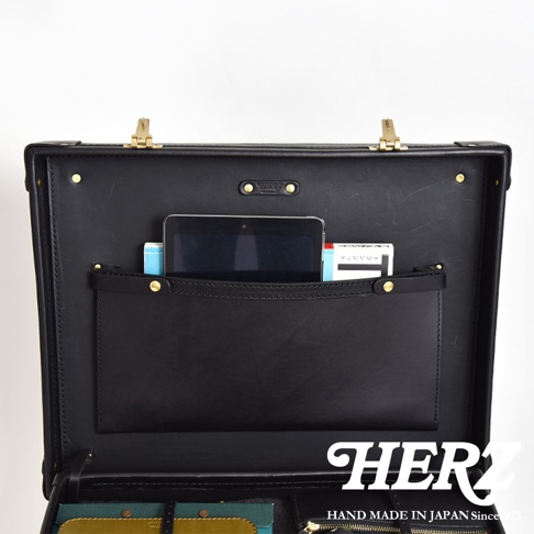 職人手作黑色皮革英倫風便攜手提行李箱，內部結構展示，包含一個平板電腦、兩本文件夾，以及一個皮革置物袋，箱體有金色鎖扣及鉚釘裝飾。