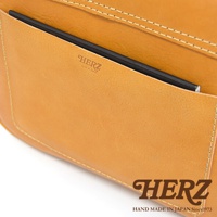 HERZ 品牌壓印和手工縫製細節，一款棕褐色皮革包的特寫。