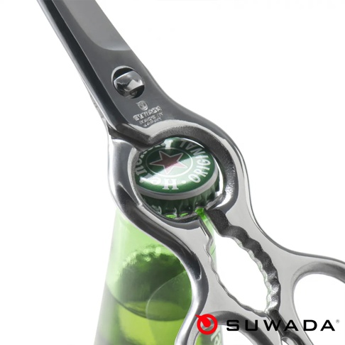 一把精緻的 SUWADA 品牌不鏽鋼多功能廚房剪刀正用於開啟一瓶海尼根啤酒，剪刀柄部設有開瓶器設計，鏡面金屬質感光亮，背景為簡潔的純白色。