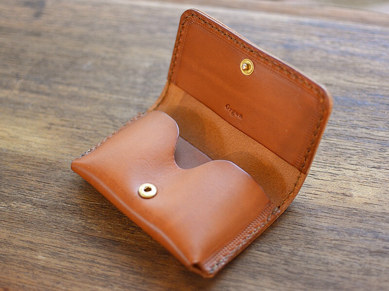 職人手作皮革Organ名片夾，淺棕色，翻蓋設計，內有兩個名片收納槽，以黃銅色按扣固定，皮革表面壓印有「Organ」品牌字樣。