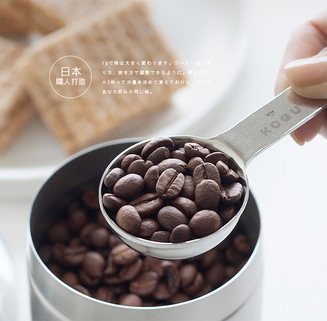 日製18-8不鏽鋼雙頭計量式咖啡豆勺，勺身刻有KOGU品牌標誌，勺內裝滿深棕色咖啡豆。