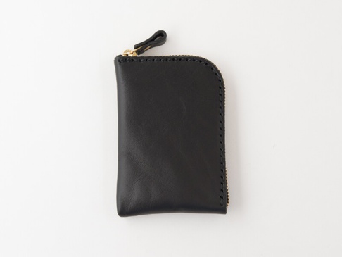 黑色皮革製成的職人手作迷你錢包，採用拉鍊開合設計，頂部有一個皮革拉環，縫線清晰可見，整體呈現簡約風格。