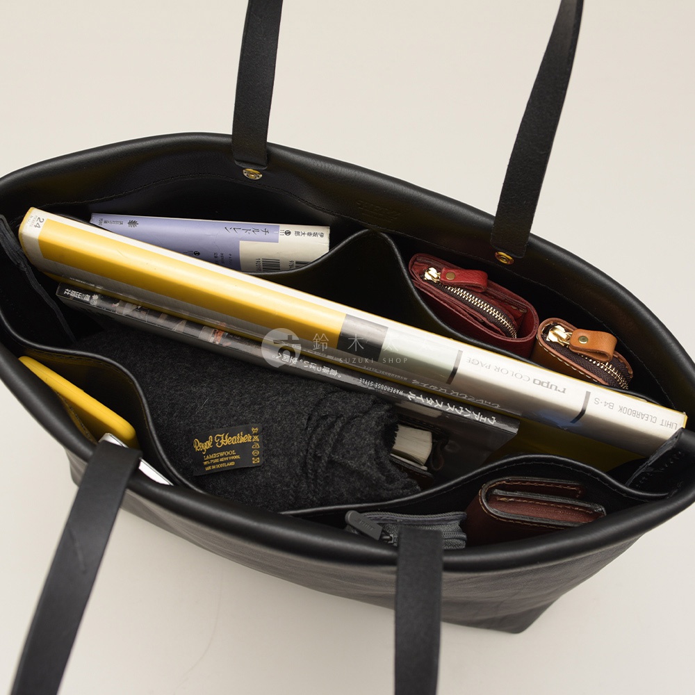 黑色皮革托特包，內部有四個隔層，可容納書籍、手機、錢包和毛料圍巾。