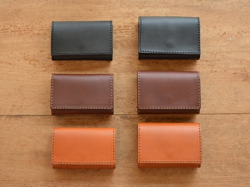 六個職人手作皮革證件收納夾，分為黑、棕、橘三種顏色，每個夾子皆以手工縫線製作，呈現簡約的設計。