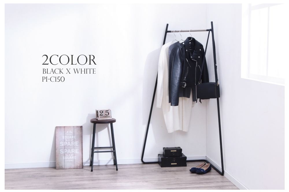 角落造型吊掛衣桿，黑色金屬材質，掛有白色長袖上衣、灰色毛衣和黑色皮夾克，並配有一個黑色包包。