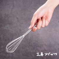 一隻手拿著一個銀色不鏽鋼攪拌棒，其末端有許多細長的鋼絲圈。