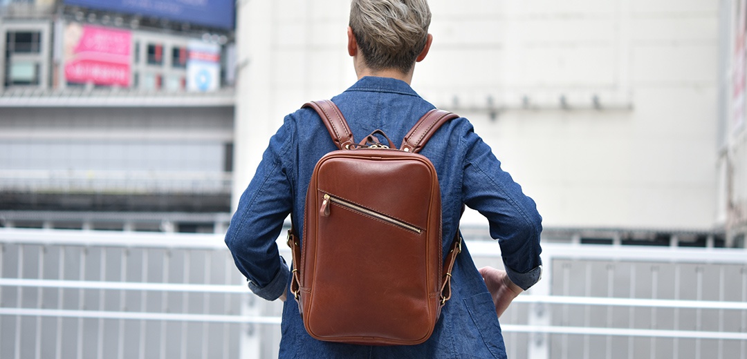 棕色皮革長方型後背包，配有可調式肩帶和外部拉鍊口袋，適合日常使用。