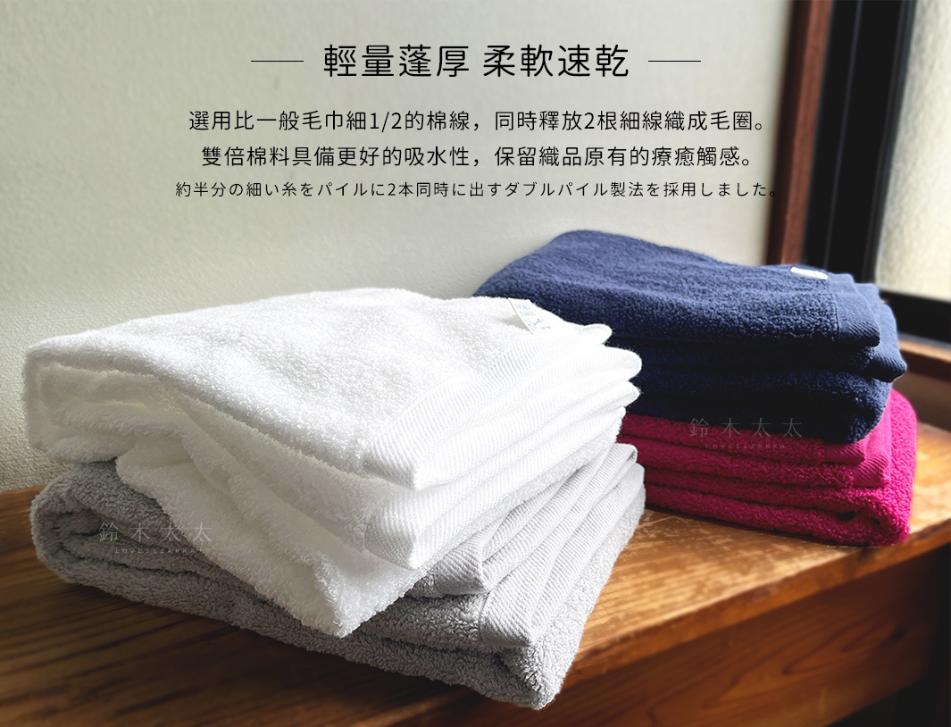 堆疊的毛巾禮盒，包含白色、灰色、深藍色和桃紅色的竹棉浴墊與細纖毛巾，質地蓬鬆柔軟。