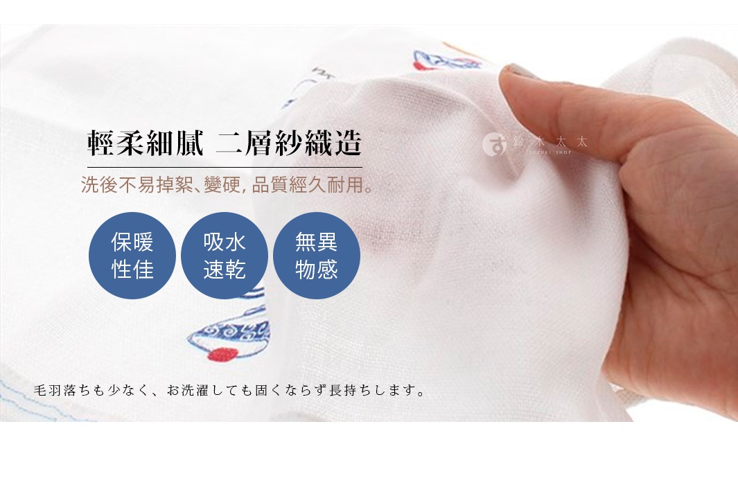 這是一塊白色的二層紗布巾，材質輕柔，帶有藍色魚紋圖案。手指正在抓握紗布巾，展示其柔軟的質地。