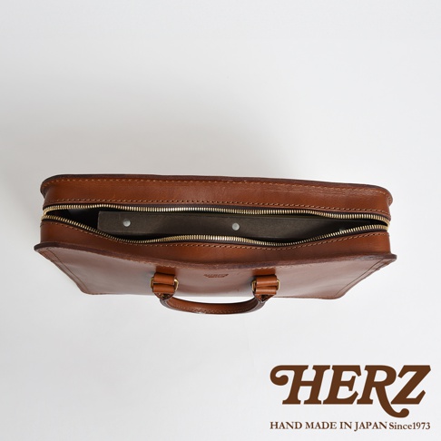 棕色皮革手提商務公事包，拉鍊部分開啟，露出內部文件夾。 雙提把設計，金屬拉鍊。