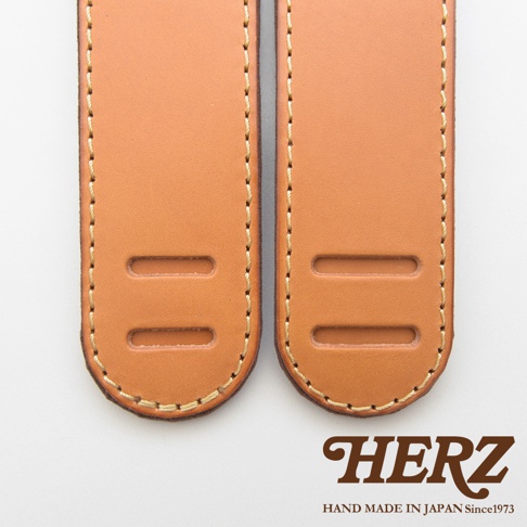 兩條淺棕色皮革製成的肩墊，帶有雙排縫線和兩個長方形開孔。